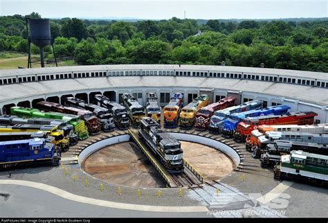 A railroad roundtable full with locomotives on a clear sunny day.